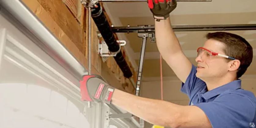 1. A technician repairing a garage door in Maryland, showcasing tools and equipment used for maintenance and service.