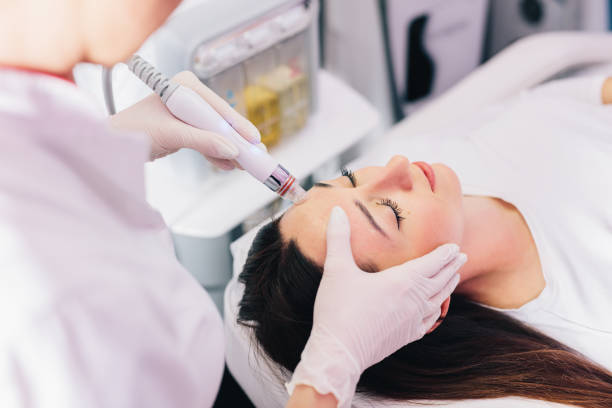 Cosmetologist doing Hydradermabrasian treatment on woman face in beauty clinic